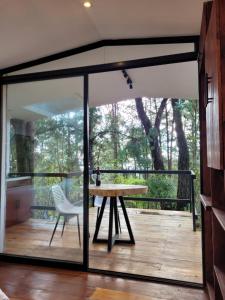 Una casa de cristal con una mesa y una silla en una terraza. en Cabaña Aventurina- La pascana Ecolodge Entorno natural excepcional, conexión con la naturaleza y avistamiento de aves, Ubicado a 3km del metrocable y Parque Arvi, Guarne, en Mazo 36 fotos más