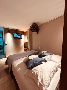 1 dormitorio con 1 cama con almohadas y TV en la pared en Renacer, Poblado Manila, en Medellín
