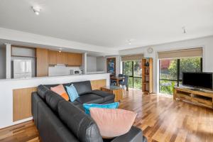 a living room with a black couch and a kitchen at Apartment 5 Pacific Apartments in Lorne