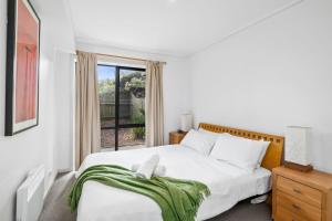a white bedroom with a bed and a window at Apartment 5 Pacific Apartments in Lorne