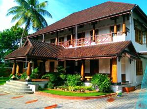 a building with a balcony and a palm tree at Azza Home in Cochin