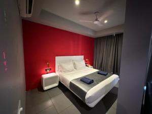 a bedroom with a bed with a red wall at SinQ Party Hotel - No Male Stags Allowed in Candolim +39 photos