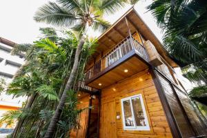 a wooden house with palm trees in front of it at SinQ Party Hotel - No Male Stags Allowed in Candolim