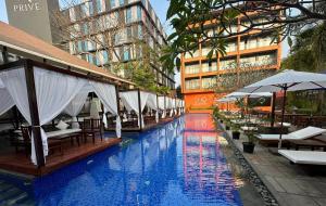 a swimming pool with tables and umbrellas next to a building at SinQ Party Hotel - No Male Stags Allowed in Candolim