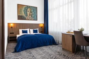 a bedroom with a blue bed and a desk with a desk at AN Hotel self check-in in Šiauliai