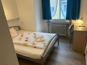 a small bed in a small room with blue curtains at Hotel Haus Schwan Köln in Cologne