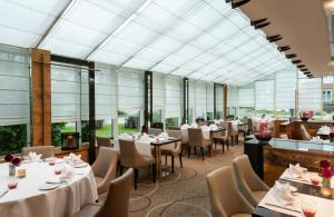 a restaurant with tables and chairs and windows at Leonardo Hotel Köln Bonn Airport in Cologne