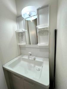 a bathroom with a white sink and a mirror at LAINA Kyobashi in Osaka