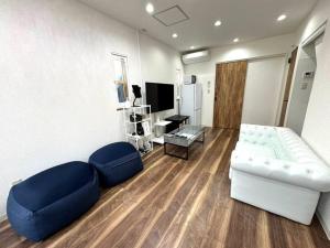 a living room with a white couch and blue chairs at LAINA Kyobashi in Osaka