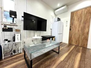 a room with a glass table with a tv on the wall at LAINA Kyobashi in Osaka