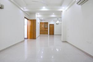 an empty hallway with white floors and wooden doors at FabHotel New Journey Hospitality Near MG Road & Sikanderpur Metro in Gurgaon