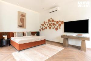 una camera da letto con un letto e una TV a schermo piatto di StayVista at Sol & Sands with Mountain View and Pool a Alibag