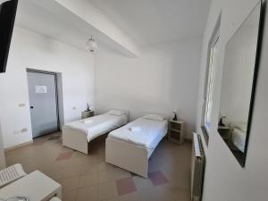 a white room with two beds and a mirror at Pensiunea Eurosan Slănic-Moldova in Slănic-Moldova