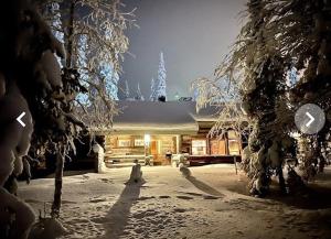 a building with snow covered trees in front of it at Ruka Villa Taikaranta in Ruka