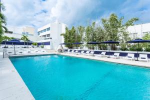 a large swimming pool with chairs and umbrellas at Albion Hotel in Miami Beach