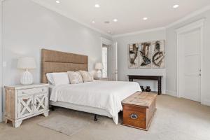 a white bedroom with a bed and a fireplace at Malibu Dunes by Fieldtrip Expansive Hamptons-Style Estate w Private Beach Backyard in Malibu