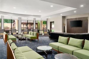 a hotel lobby with green couches and a flat screen tv at Courtyard Richmond North/Glen Allen in Richmond
