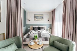 ein Schlafzimmer mit einem Bett und zwei Stühlen und einem Tisch in der Unterkunft Apartamenty z Jakuzzi Perłowa Przystań Rent Kołłątaja in Kołobrzeg