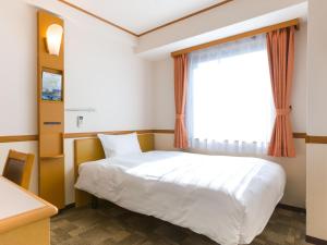 a bedroom with a white bed and a window at Toyoko Inn Saitama Toda koen eki Nishi guchi in Toda