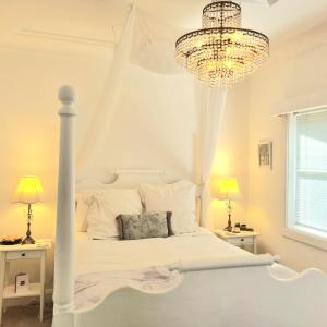 a bedroom with a white bed and a chandelier at Dalia's Blue Mountain Retreat in Katoomba