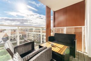 ein Balkon mit Tisch und Stühlen und einem großen Fenster in der Unterkunft Apartamenty z Jakuzzi Perłowa Przystań Rent Kołłątaja in Kołobrzeg