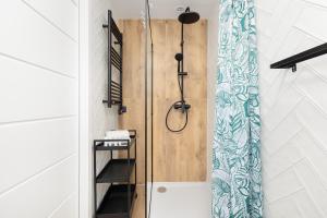 a shower with a wooden door in a bathroom at Apartament Bałtycki Zakątek by Noclegi Renters in Dziwnów