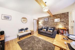 a living room with a couch and a stone wall at Host & Stay - Batemill Cottage in Birch Vale