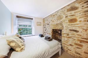 a bedroom with a stone wall next to a bed at Host & Stay - Batemill Cottage in Birch Vale
