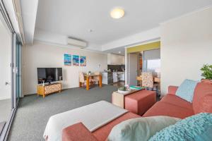 a living room with a red couch and a tv at 5 Star Mandurah Beach Exclusive Apt in Mandurah
