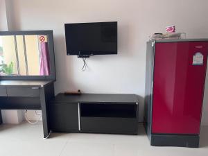 a room with a tv and a desk and a refrigerator at KC Kamala Guesthouse in Kamala Beach