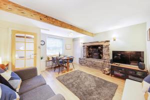 a living room with a couch and a tv and a fireplace at Host & Stay - Batemill Cottage in Birch Vale