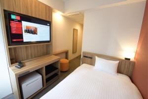 a hotel room with a bed and a flat screen tv at Hakata Green Hotel Tenjin in Fukuoka +16 photos