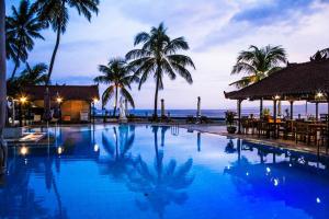 a large swimming pool with palm trees and the ocean at Studio Pelangi - Candidasa in Candidasa