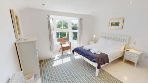 a bedroom with a bed and a chair and a window at Georgeham Windsor Cottage 3 Bedrooms in Georgeham