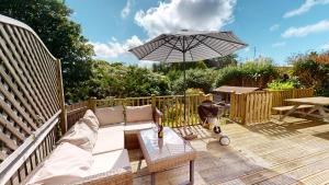 a patio with a couch and an umbrella and a table at Georgeham Windsor Cottage 3 Bedrooms in Georgeham