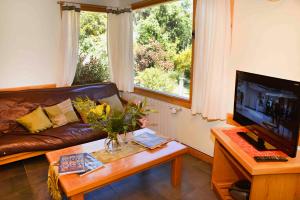 un salon avec un canapé, une table et une télévision dans l'établissement Matices Patagonicos, à San Carlos de Bariloche