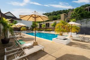 una piscina con tumbonas y sombrilla y una piscina en Beachside Apt Short Walk to Nai Harn Beach 2-3 BR, en Nai Harn Beach