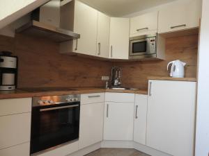 eine Küche mit weißen Schränken und einer Mikrowelle in der Unterkunft Ferienwohnung Saalfeld in Schillig