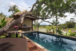 a resort with a swimming pool and a tree at Temuku Villas Ubud - CHSE Certified in Ubud