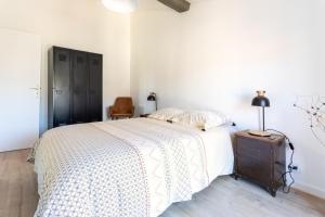 Un dormitorio con una cama y una lámpara en un tocador en Vermeille - Appt 2p avec jolie vue, en Céret