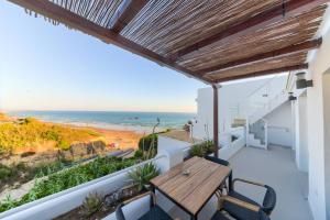 a balcony with a wooden table and chairs and the beach at Villas Flamenco Beach Conil in Conil de la Frontera