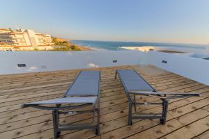 two chairs and a table on a deck with the beach at Villas Flamenco Beach Conil in Conil de la Frontera