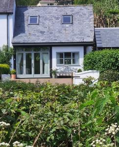une maison avec une bande de buissons devant elle dans l'établissement Keep Cottage, à Southleigh