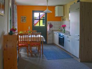 a kitchen with a table and chairs and a kitchen with orange walls at Ferienwohnung Petra Bargel "die Nr 1"in Speck in Speck +2 photos