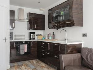 a kitchen with wooden cabinets and a sink and a couch at The Old Post Office 23 High Street in Cemaes Bay +16 photos
