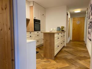 a kitchen with white cabinets and a wooden floor at Churfirsten Panorama - CharmingStay in Flumserberg +5 photos