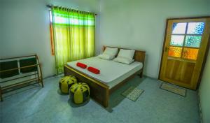 a bedroom with a bed with two red pillows and a window at Janali Homestay in Kandy