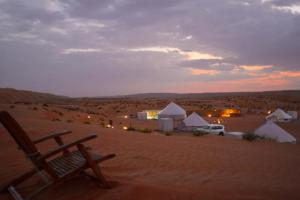BadīyahにあるDesert Stars Campの夕暮れの砂漠の真ん中にある椅子