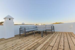 a bench on a wooden deck with a lighthouse at Villas Flamenco Beach Conil in Conil de la Frontera