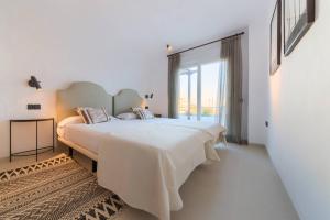 a white bedroom with a large bed and a large window at Villas Flamenco Beach Conil in Conil de la Frontera